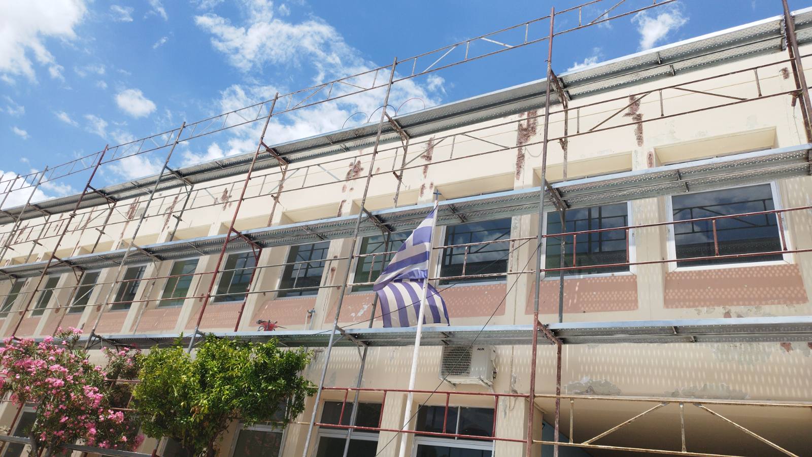 Πλάγια όψη κτιρίου με ελληνική σημαία, εργασίες μόνωσης προσόψεως